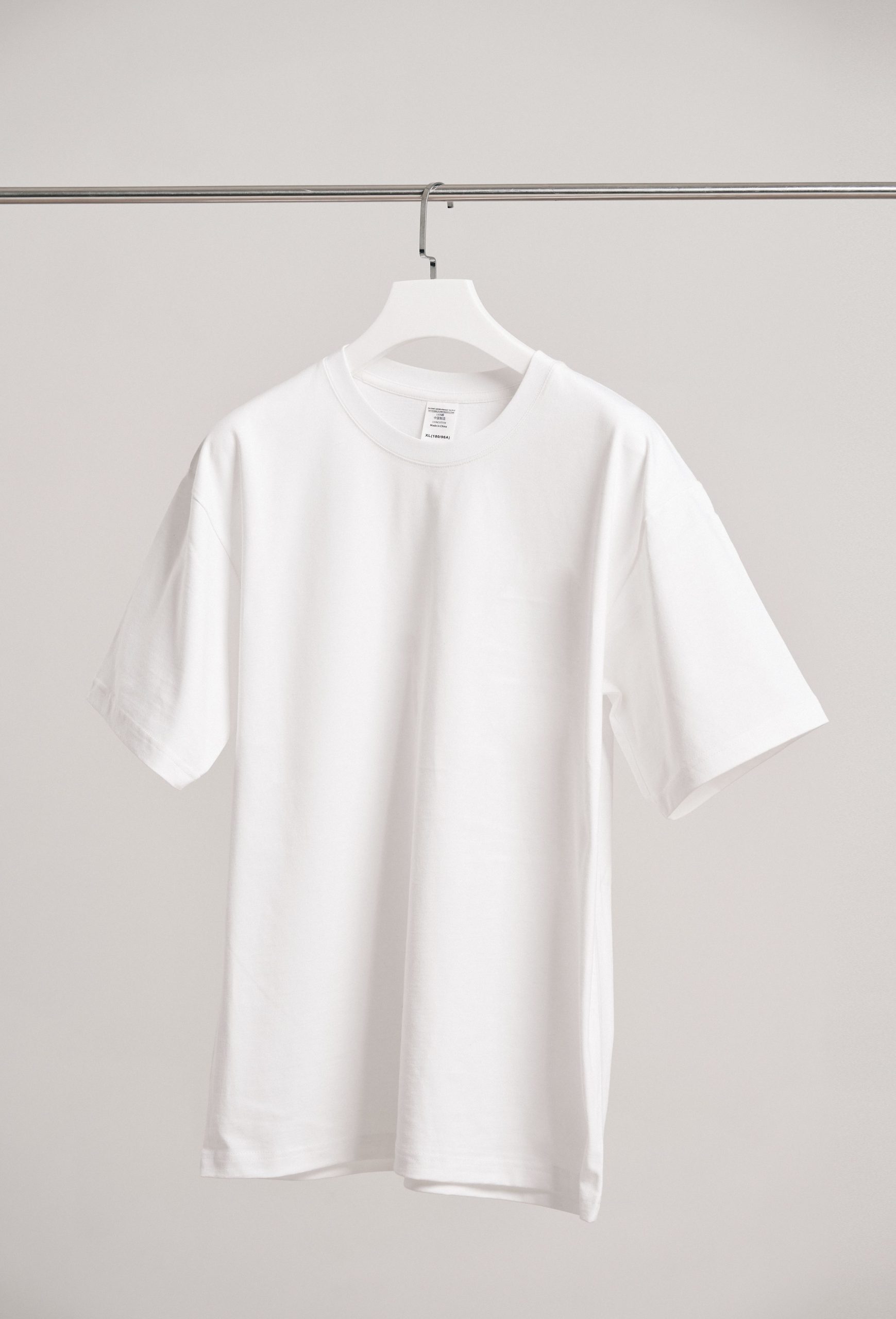 Simple white t-shirt hanging in a modern Shanghai boutique, emphasizing fashion minimalism.