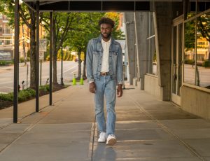 Man in denim walking on a city sidewalk showcasing urban style.