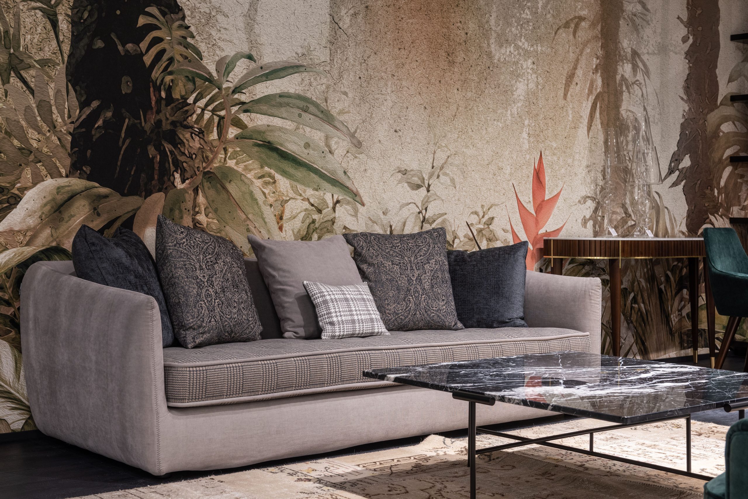 pexels-photo-6758245-6758245 Comfortable sofa with pillows placed at wall with painted leaves in modern spacious room with table on rug at home